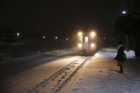 A woman stands on a snow-covered platform as a train approaches a station Feb. 3, 2020, in Biei, central Hokkaido, Japan. (AP Photo/Jae C. Hong)