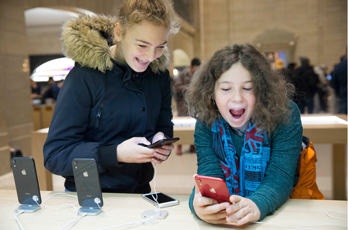 Two young people having fun while playing with new iPhones in an Apple Store.