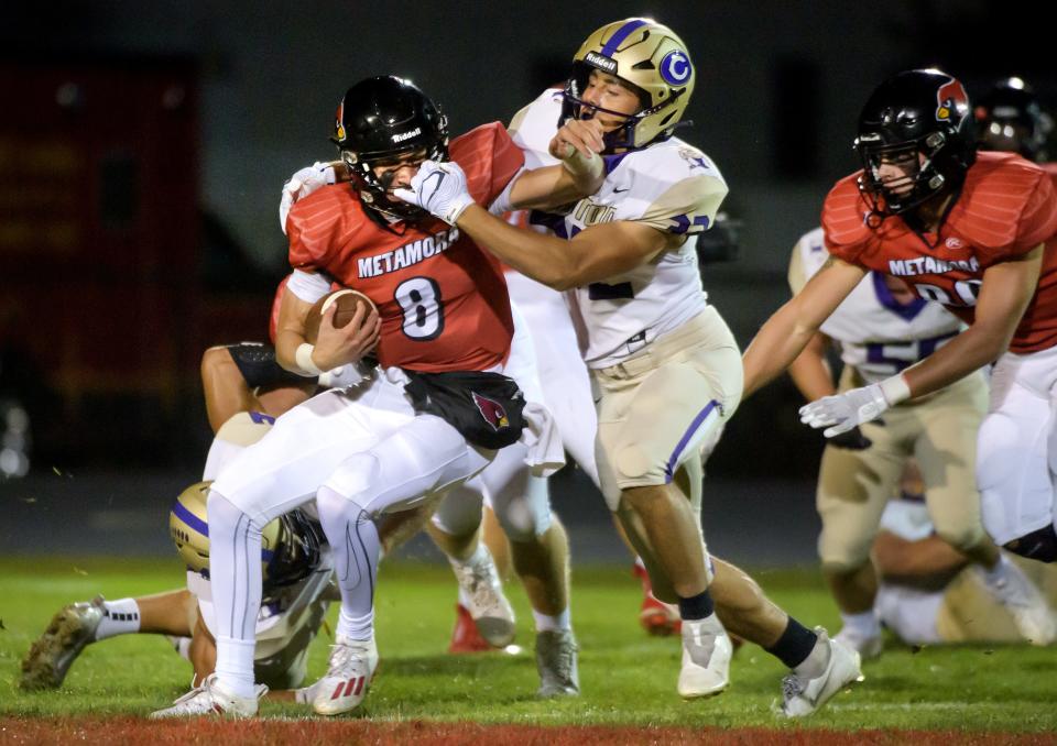 Metamora quarterback Kaden Hartnett (8) grapples with Canton's Joseph Norton in the first half Friday, Sept. 23, 2022 in Metamora.