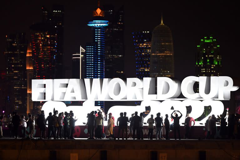 Los aficionados se paran frente al cartel &quot;Fifa Wordcup Qatar 2022&quot; en el Doha Corniche antes del Mundial