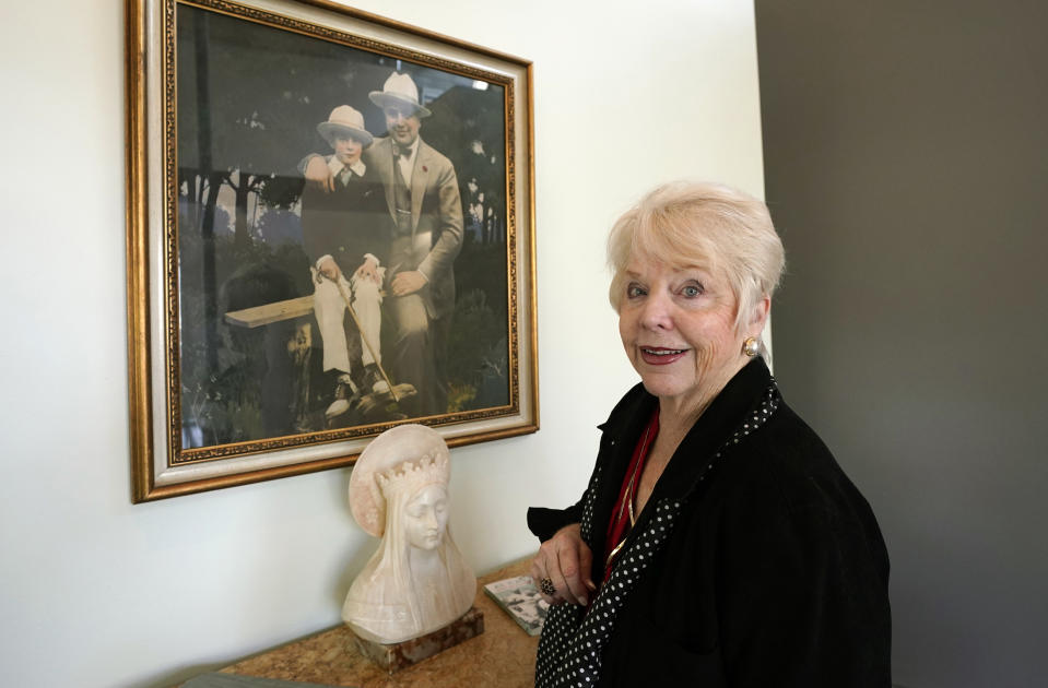 Diane Capone discusses her family near a photograph of her father, Albert "Sonny" Capone, as a young boy and her grandfather Al Capone on display at Witherell's Auction House in Sacramento, Calif., Wednesday, Aug. 25, 2021. The granddaughter of the famous mob boss and her two surviving sisters will sell 174 family heirlooms at an Oct. 8 auction titled "A Century of Notoriety: The Estate of Al Capone, that will be held by Witherell's in Sacramento. (AP Photo/Rich Pedroncelli)