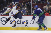 Vancouver Canucks' Luke Schenn, right, checks St. Louis Blues' Logan Brown during the third period of an NHL hockey game in Vancouver, British Columbia, Sunday, Jan. 23, 2022. (Darryl Dyck/The Canadian Press via AP)