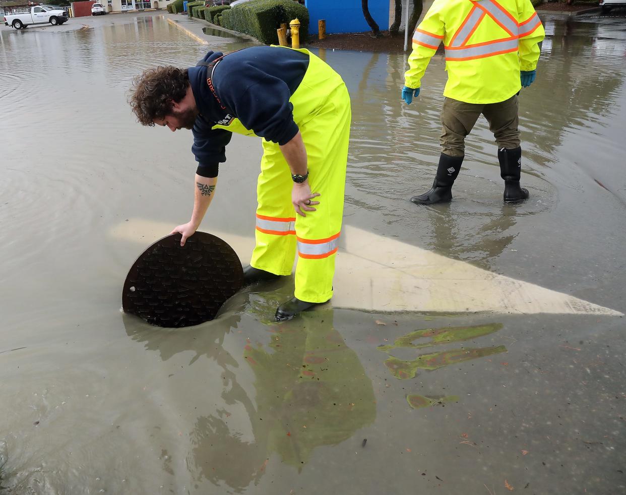 Zachary King, of Port Orchard Public Works, holds open a manhole cover as crews work to drain the flood water closing Bay Street in downtown Port Orchard on Tuesday, Dec. 27, 2022