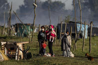 Una familia con su perro se para con sus pertenencias después de que su choza fuera destruida por la policía durante el desalojo de un campamento de ocupantes ilegales en Guernica, provincia de Buenos Aires, Argentina, el jueves 29 de octubre de 2020. (AP Foto/Natacha Pisarenko)