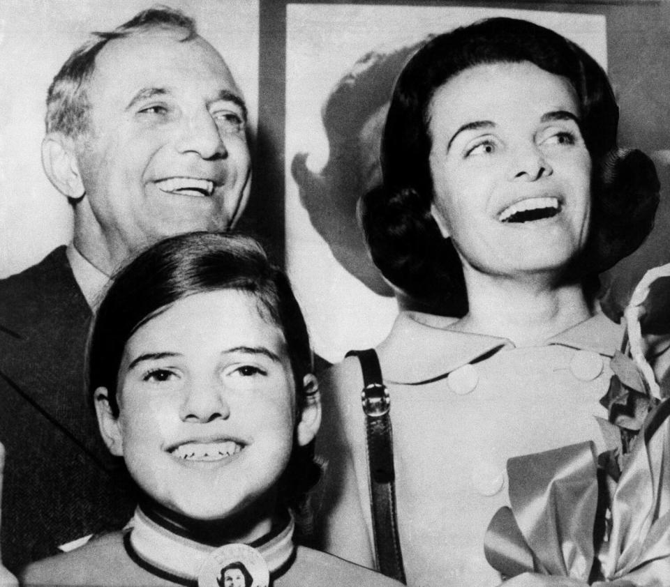 A black-and-white image of a man, woman and young girl, all smiling.