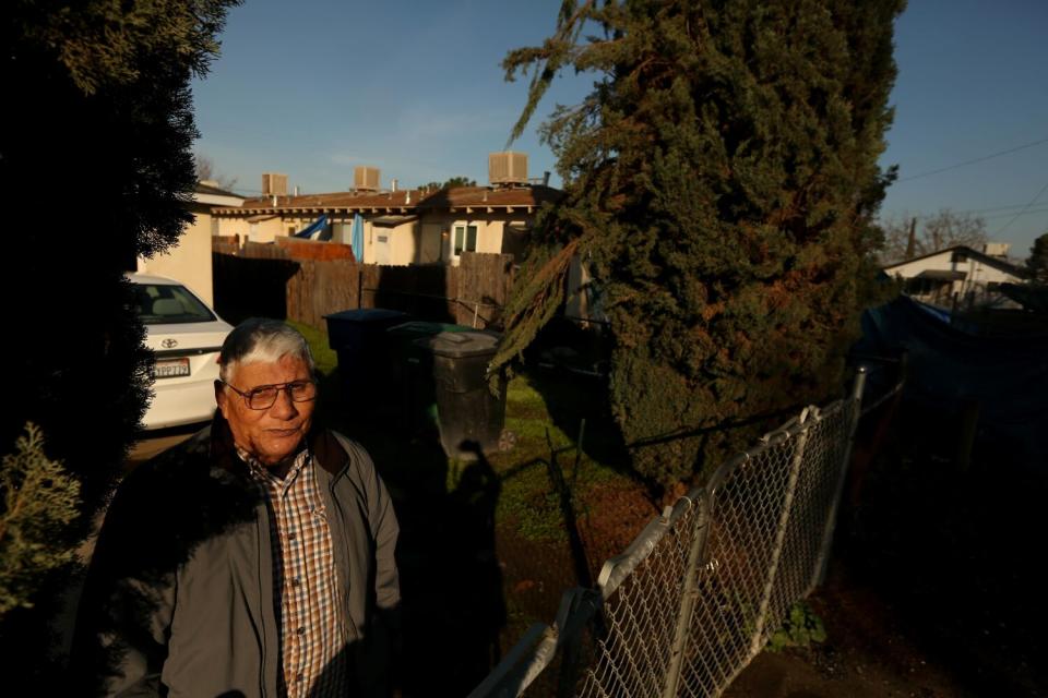 A man stands outside a house in a neighborhood