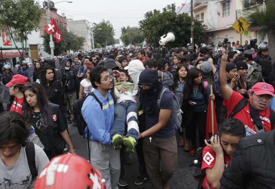 Demonstrators carry a fellow demonstrator who was injured earlier during a protest over the 43 missing Ayotzinapa students, in Mexico City