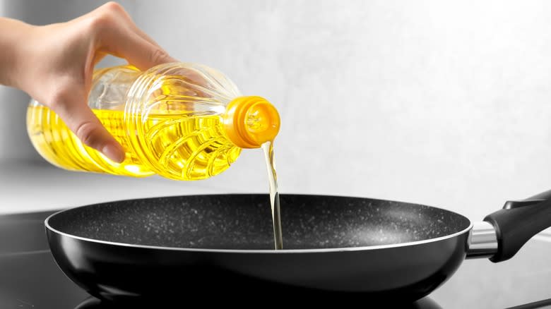 person pouring oil into pan