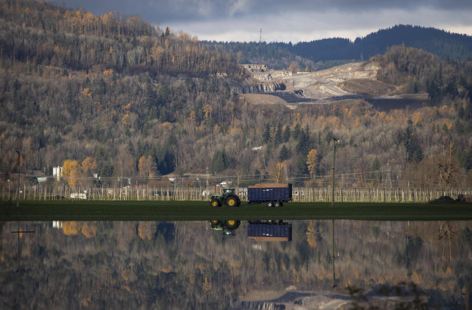 A tractor tows a trailer full of feed past flooded farmland following heavy rains in Abbotsford, British Columbia, Friday, Nov. 19, 2021. (Darryl Dyck/The Canadian Press via AP)