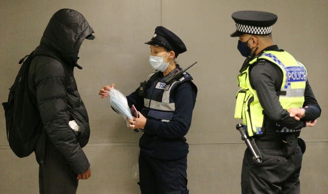 A man is given a face mask to wear after being issued with a fine for not being in possession of and not wearing a face mask (Jonathan Brady/PA)