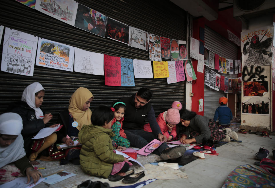 In this Tuesday, Jan. 21, 2020 photo, young girls draw sketches near the protest site in New Delhi's Shaheen Bagh area, India. Muslim women are transcending the confines of their homes to lay claim to the streets of this nondescript Muslim neighborhood in the Indian capital and slowly transforming it into a nerve center of resistance against a new citizenship law that has unleashed protests across the country. The women, sitting in the middle of a major highway, have taken turns maintaining an around the clock sit-in for more than a month. They sing songs of protest and chant anti-government slogans, some cradling babies, others laying down rugs to make space for more people to sit. (AP Photo/Altaf Qadri)