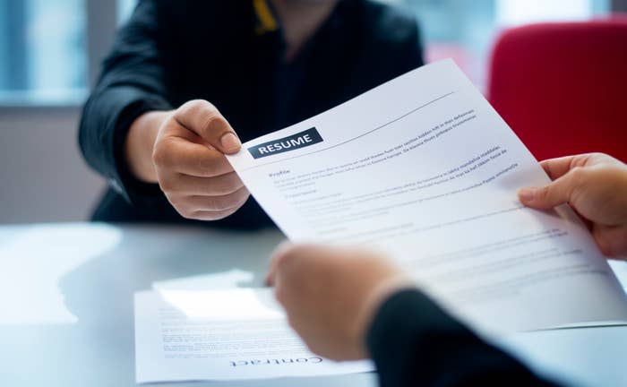 person handing their résumé to a recruiter