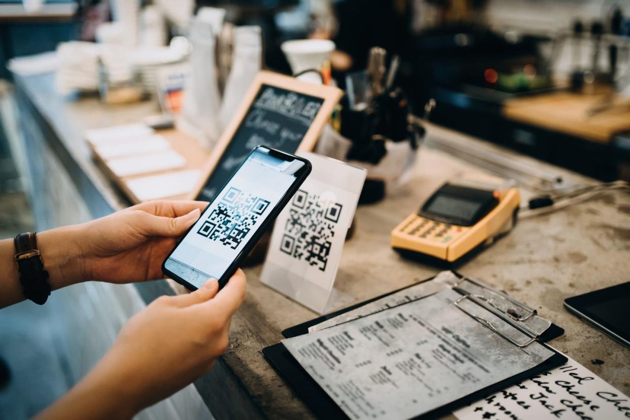 customer scanning qr code, making a quick and easy contactless payment with her smartphone in a cafe