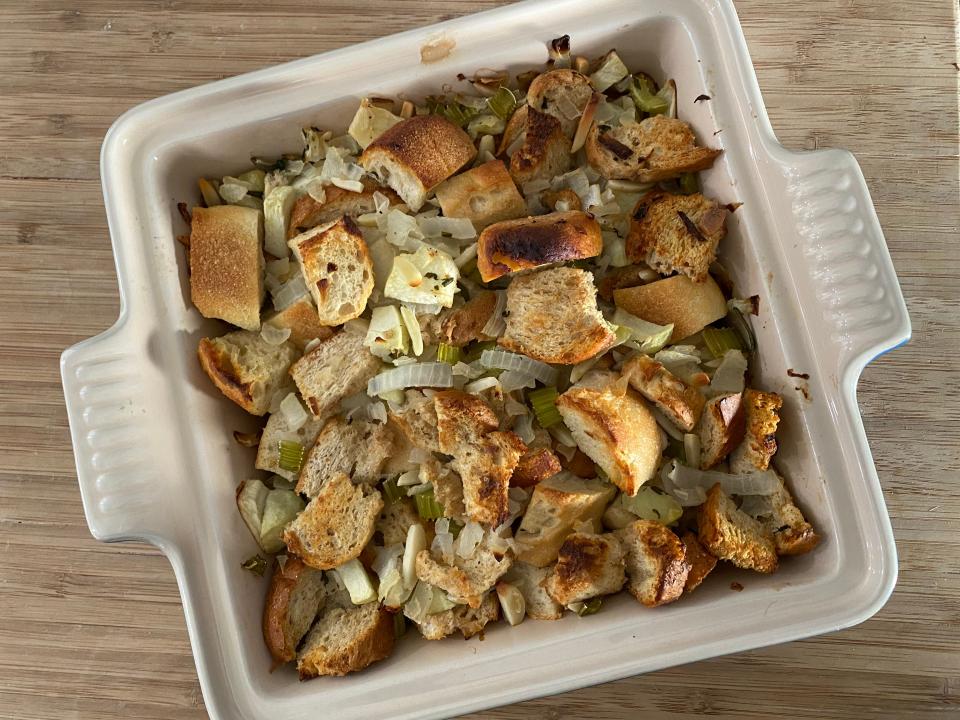 Ina Garten's stuffing cooked in a white baking dish on a wooden cutting board