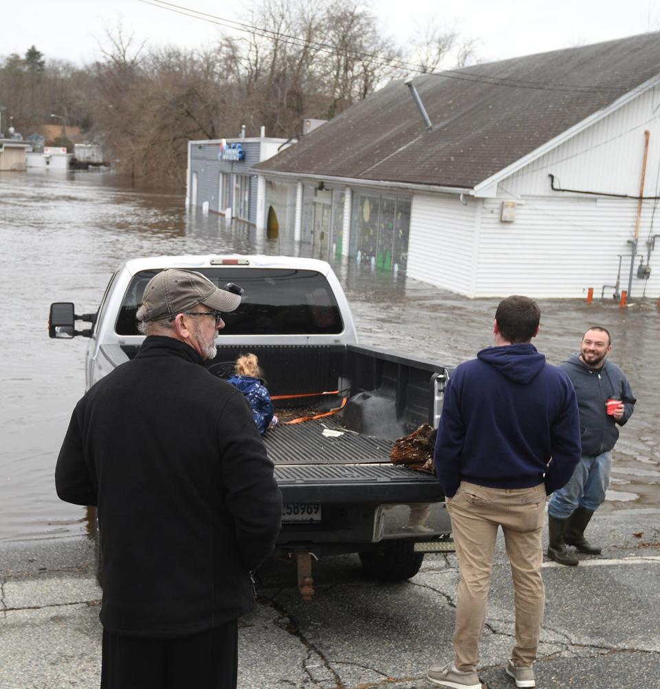 Keith Santor, of Norwich, right, is all smiles after Yantic Fire Engine Company #1 personnel rescued him and another man by boat from Domino's by Norwichtown Commons Wednesday as the Yantic River overflowed its banks.