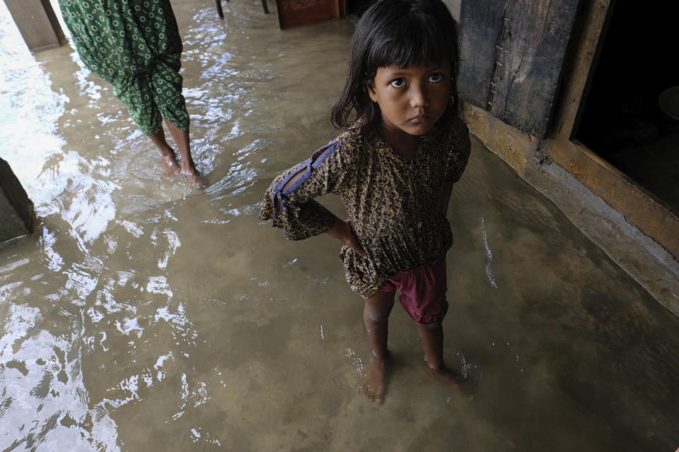 A girl reacts to camera as he family members inspect their damaged belongings at her home as flood water levels recede slowly in Sylhet, Bangladesh, Wednesday, June 22, 2022. (AP Photo/Mahmud Hossain Opu)