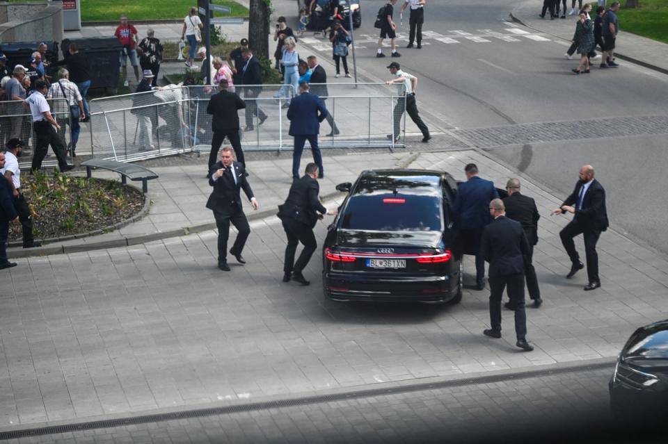 Security officers move the Slovakian PM in a car after the shooting (REUTERS)