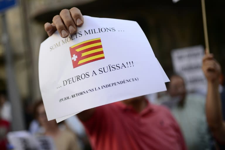 An opponent of the Catalan region's independence bid holds a banner reading "We are many million... euros in Switzerland" in Barcelona on July 30, 2014