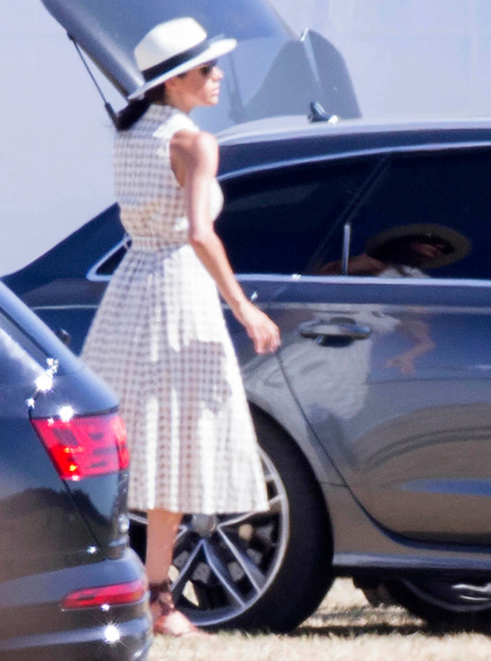 On Saturday, Meghan Markle wore a pretty summer dress with a hate and lace-up sandals. [Photo: Rex]