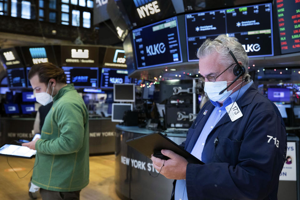 In this photo provided by the New York Stock Exchange, Frank O.Connell, right works with a feel trader on the floor, Tuesday, Jan. 12, 2021. U.S. stocks are drifting near their record heights Tuesday, while Treasury yields keep marching higher amid expectations that the economy will pull out of its slump after a powerful recovery sweeps the globe later this year. (Colin Ziemer/New York Stock Exchange via AP)