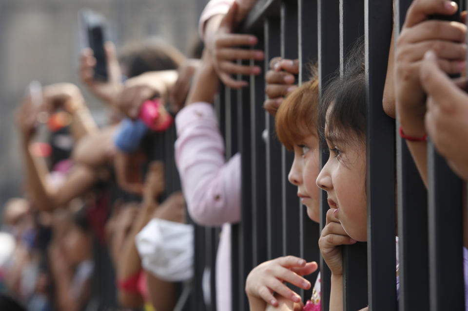 Children watch a Day of the Dead parade in Mexico City, Sunday, Oct. 27, 2019. The parade on Sunday marks the fourth consecutive year that the city has borrowed props from the opening scene of the James Bond film, "Spectre," in which Daniel Craig's title character dons a skull mask as he makes his way through a crowd of revelers. (AP Photo/Ginnette Riquelme)