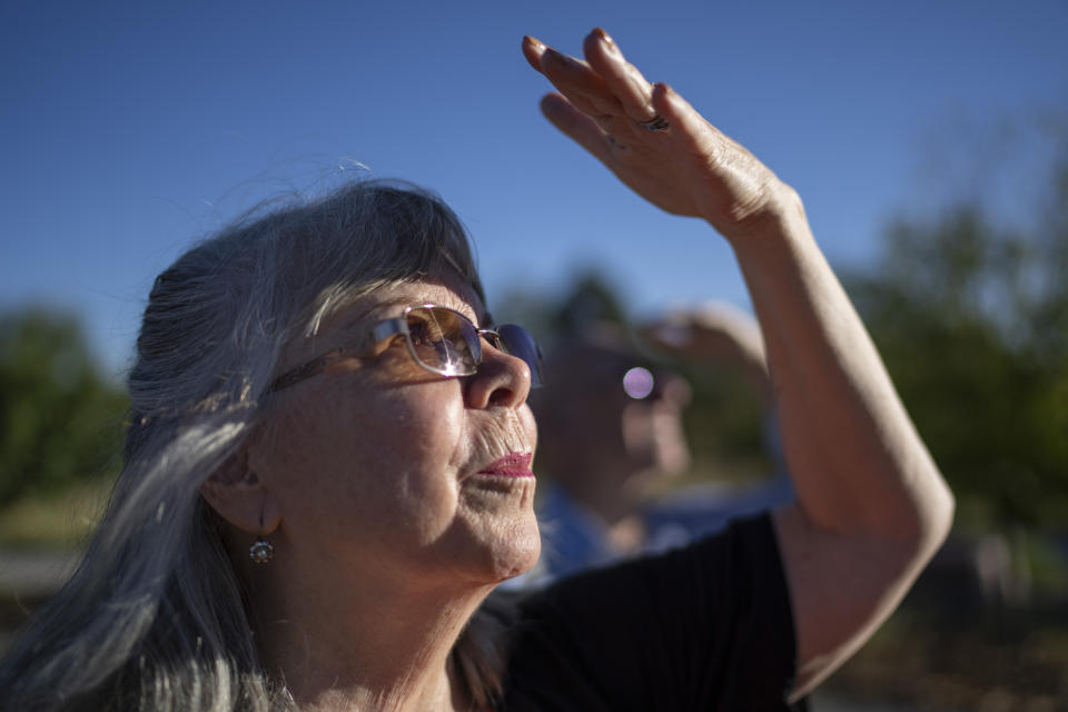 On Tuesday, Sept. 5, 2023, Sandy Phillips looks up at the crane sculptures ascending to the sky as part of the memorial garden in Aurora, Colo., honoring the victims of the 2012 mass shooting at an Aurora movie theater, including her daughter, Jessica Ghawi. Suffering through their own personal loss, the couple set out to help other parents like them, traveling to shooting sites around the country. The trip continued for a decade. (AP Photo/David Goldman)