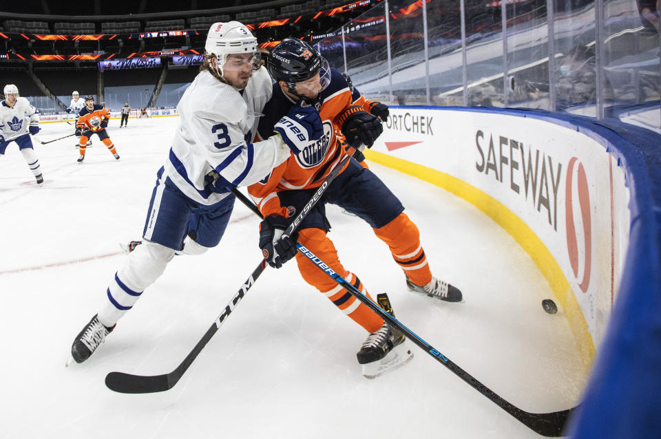 Edmonton Oilers' Alex Chiasson (39) and Toronto Maple Leafs' Justin Holl (3) battle for the puck during the second period of an NHL game in Edmonton, Alberta, on Saturday, Feb. 27, 2021. (Jason Franson/The Canadian Press via AP)