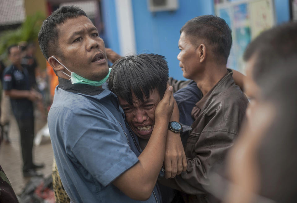 In this Sunday, Dec. 23, 2018, file photo, a man reacts after identifying his relative among the bodies of tsunami victims in Carita, Indonesia. The tsunami that hit the coasts of Indonesian islands along the Sunda Strait was not big but it was destructive. The waves smashed onto beaches in the darkness Saturday night without warning, ripping houses and hotels from their foundations in seconds and sweeping terrified concertgoers into the sea. (AP Photo/Fauzy Chaniago, File)
