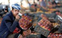 Fruit vendor chews qat, a mild stimulant, as he looks on at a fruit market amid concerns of the spread of the coronavirus disease (COVID-19) in Sanaa