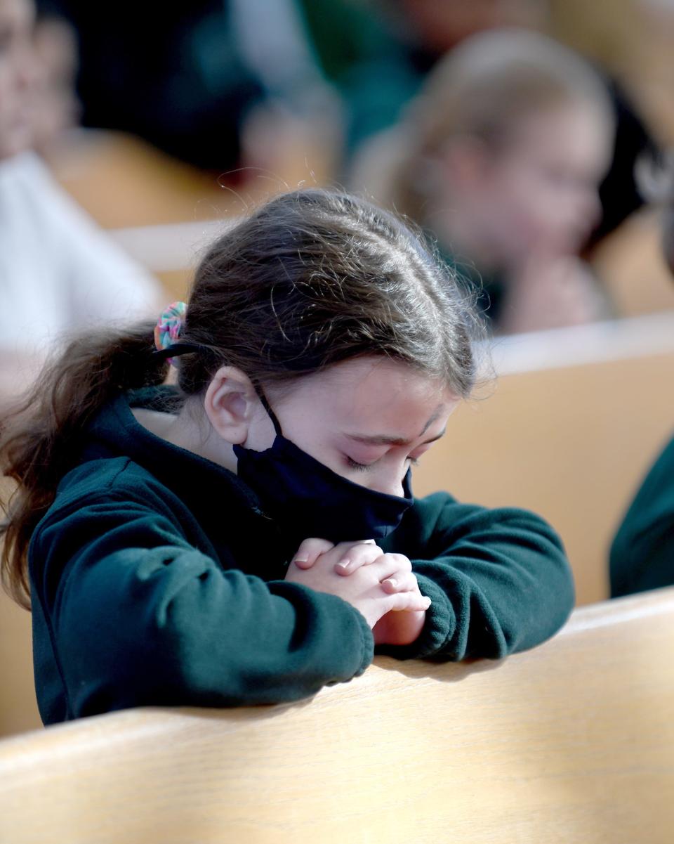 Rylee White, a fourth grader at St. Michael the Archangel Catholic School, prays with ashes on her forehead during Ash Wednesday Mass at St. Michael Church in Plain Township.