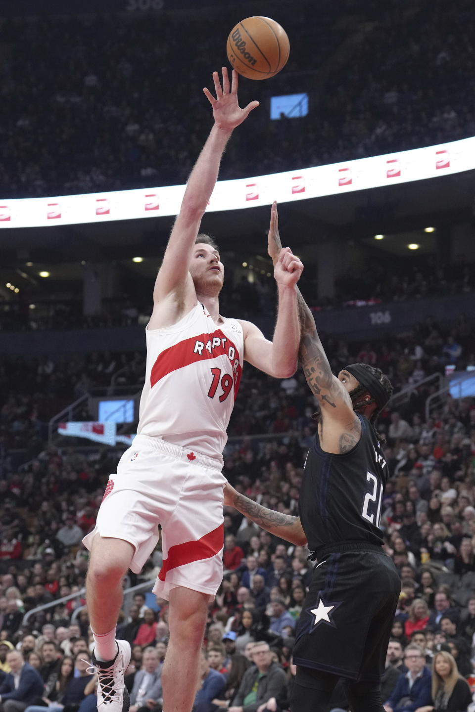 Toronto Raptors' Jacob Poeltl (19) scores on Orlando Magic's Markelle Fultz during the first half of an NBA basketball game in Toronto on Tuesday, Feb. 14, 2023. (Chris Young/The Canadian Press via AP)