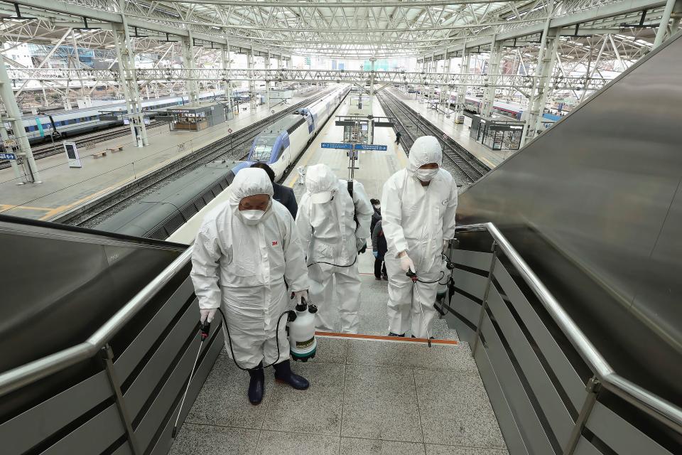 Workers wearing protective gears spray disinfectant as a precaution against the new coronavirus at Seoul Railway Station in Seoul, South Korea, Feb. 25, 2020.