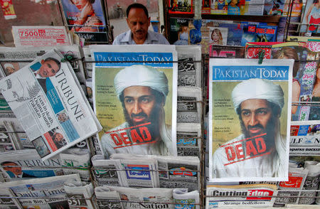 FILE PHOTO: A roadside vendor sells newspapers with headlines about the death of al Qaeda leader Osama bin Laden, in Lahore May 3, 2011. REUTERS/Mohsin Raza/File Photo