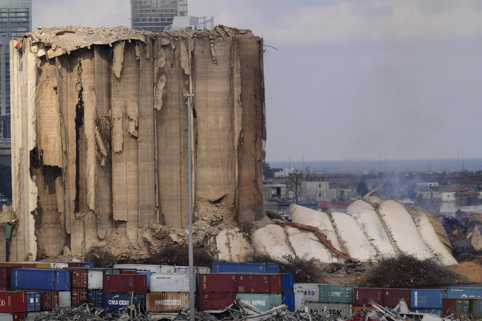 A collapsed portion, right, lies on the ground of the silos that damaged during the August 2020 massive explosion in the port, in Beirut, Lebanon, Tuesday, Aug. 23, 2022. The ruins of the Beirut Port silos' northern block that withstood a devastating port explosion two years ago has collapsed. The smoldering structure fell over on Tuesday morning into a cloud of dust, leaving the southern block standing next to a pile of charred ruins. (AP Photo/Hussein Malla)