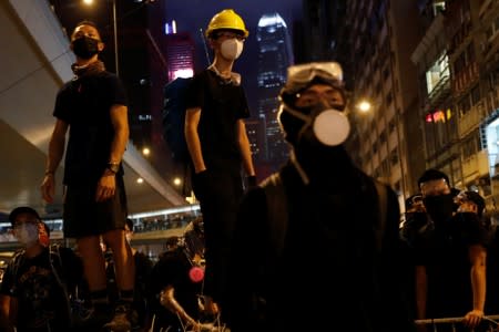 Anti-extradition bill demonstrators stay on barriers as they face riot police, after a march to call for democratic reforms, in Hong Kong