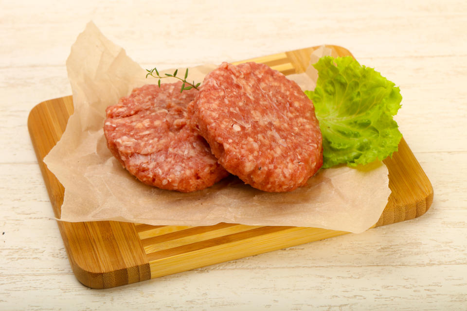 It's important to keep raw meat, like ground beef hamburger patties, on separate cutting boards and plates away from vegetables or cooked food. (Photo via Getty Images)