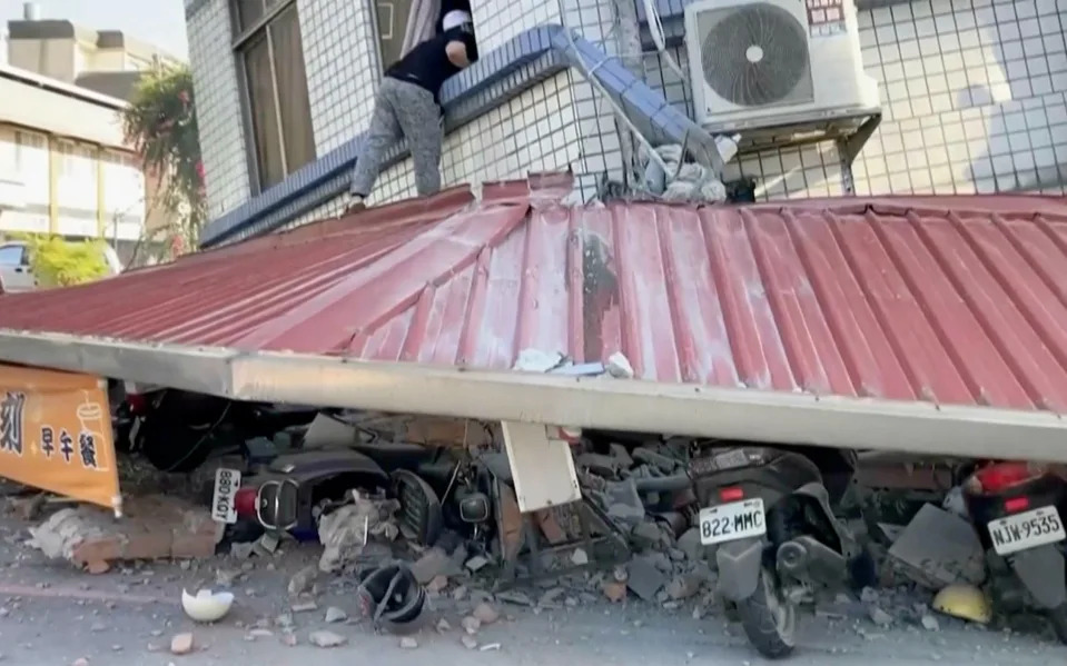 A man checks a partially collapsed building in Hualien for survivors . . .