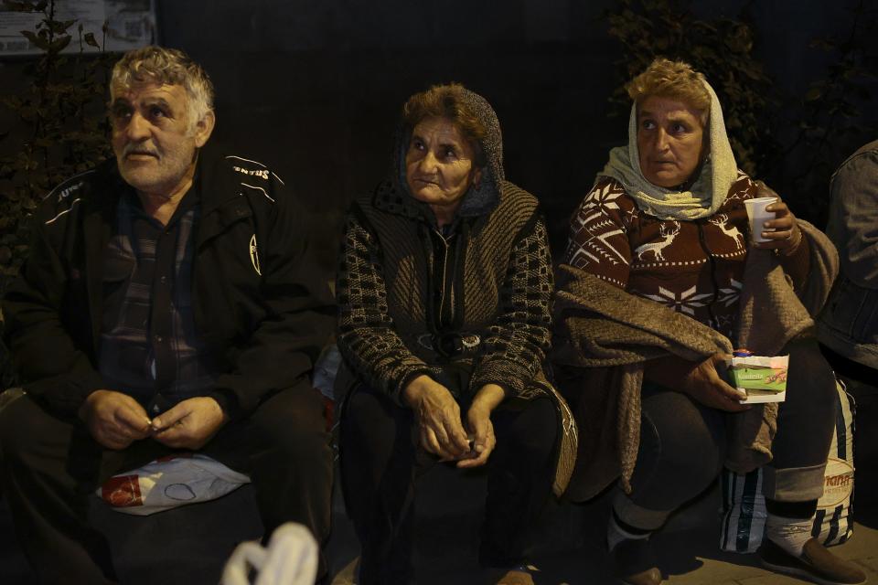 Ethnic Armenians from Nagorno-Karabakh sit near a tent camp after arriving to Armenia's Goris in Syunik region, Armenia, late Friday, Sept. 29, 2023. Armenian officials say that by Friday evening over 97,700 people had left Nagorno-Karabakh. The region's population was around 120,000 before the exodus began. (AP Photo/Vasily Krestyaninov)