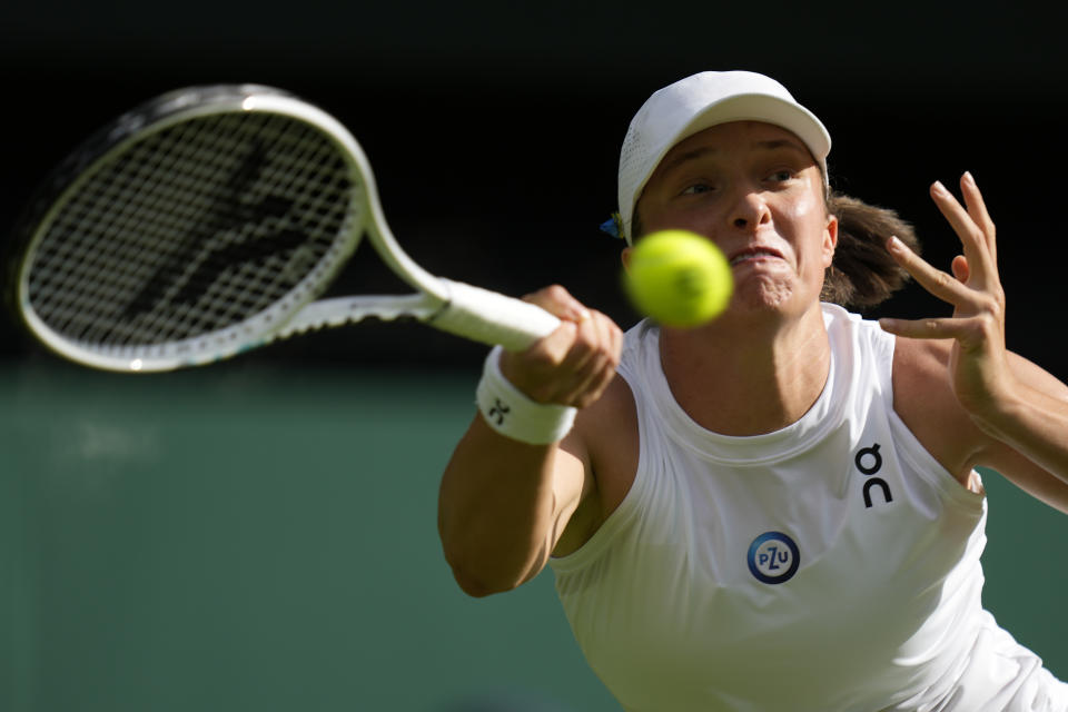 Poland's Iga Swiatek returns to Switzerland's Belinda Bencic in a women's singles match on day seven of the Wimbledon tennis championships in London, Sunday, July 9, 2023. (AP Photo/Kirsty Wigglesworth)