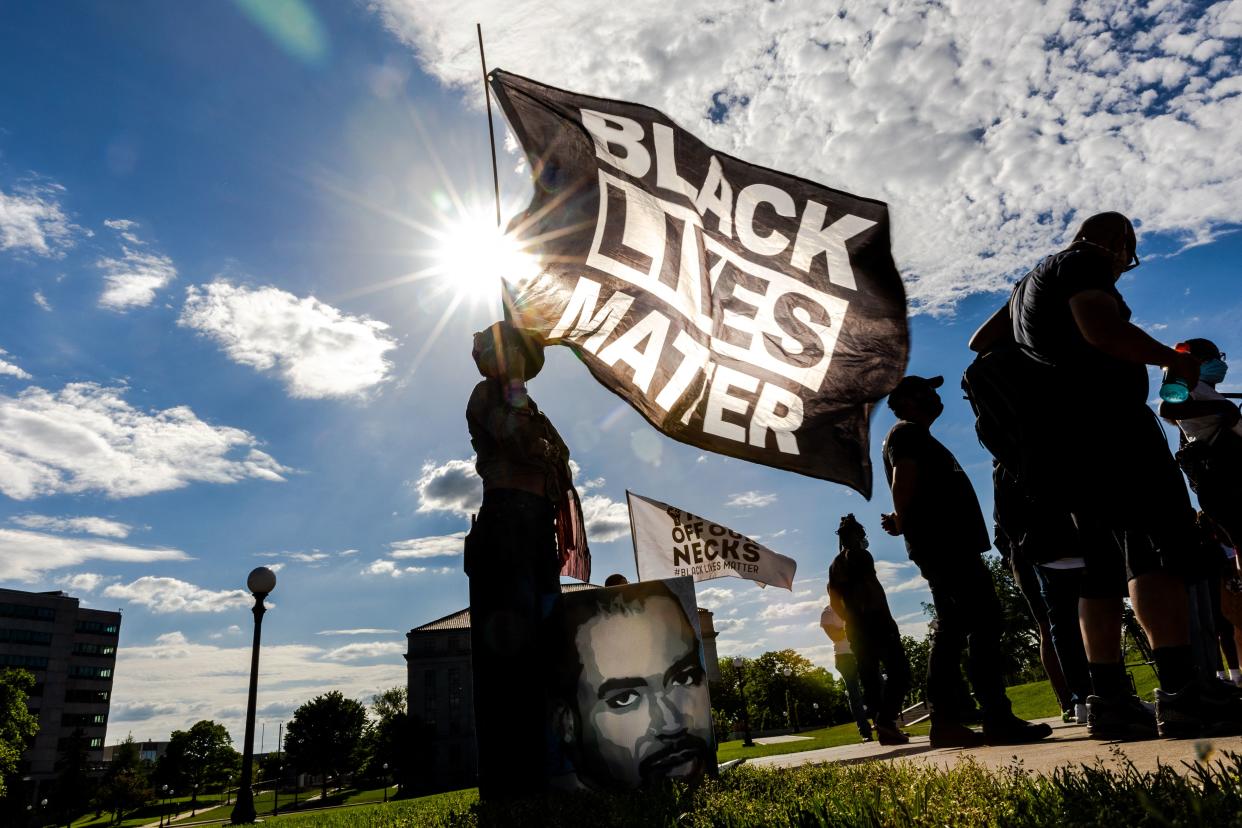 A woman holds a Black Lives Matter flag during an event in remembrance of George Floyd outside the Minnesota state capitol in St. Paul, Minn., in 2021. 