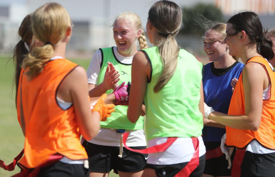 LB Alana Taylor laughs in a huddle with other members of the girls' flag football team on Eastmark High School's field in Mesa on Aug. 7, 2023.