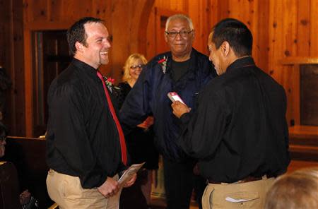 Darren Black Bear (R) reads his vows from his cellphone to Jason Pickel (L) as they are married by Darren's father Rev. Floyd Black Bear (C) in El Reno, Oklahoma October 31, 2013. REUTERS/Rick Wilking