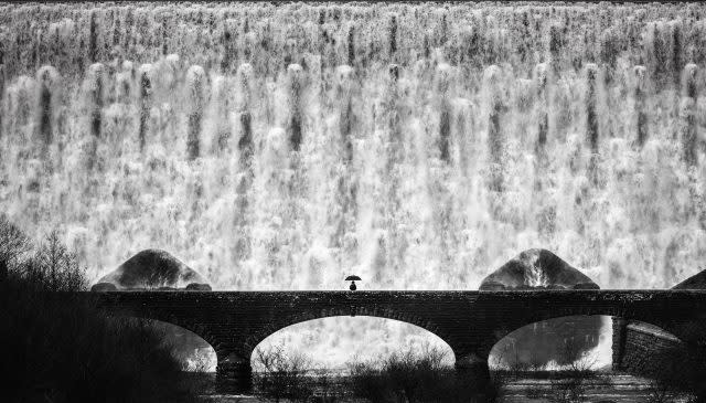 person crossing a bridge in front of a torrent in Elan Valley, Wales