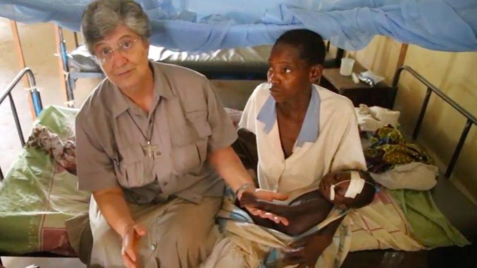 Sister Laura Gemignani, left, seen here at the hospital she runs in Nzara, South Sudan, with 20-month-old Josephine Moses and her mother, is now back in Italy, on a ventilator in critical condition from COVID-19.