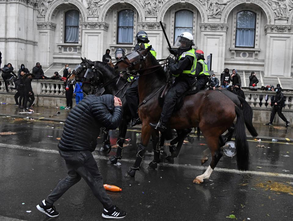 A protestor reacts as a mounted police officer raises their baton whilst riding along Whitehall, past the entrance to Downing Street, in central London on June 6, 2020, during a demonstration organised to show solidarity with the Black Lives Matter movement in the wake of the killing of George Floyd, an unarmed black man who died after a police officer knelt on his neck in Minneapolis. - The United States braced Friday for massive weekend protests against racism and police brutality, as outrage soared over the latest law enforcement abuses against demonstrators that were caught on camera. With protests over last week's police killing of George Floyd, an unarmed black man, surging into a second weekend, President Donald Trump sparked fresh controversy by saying it was a "great day" for Floyd. (Photo by DANIEL LEAL-OLIVAS / AFP) (Photo by DANIEL LEAL-OLIVAS/AFP via Getty Images)