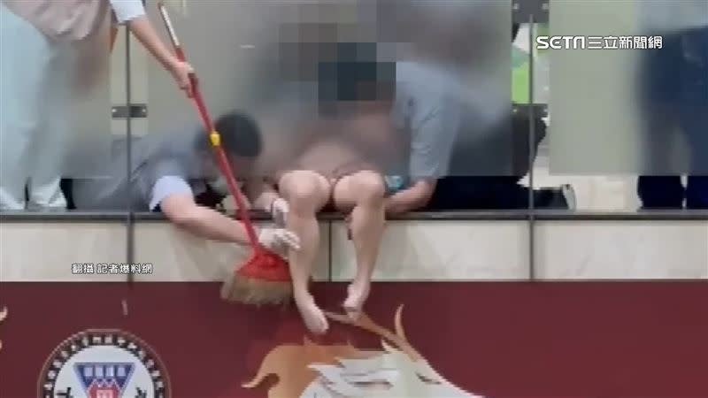 醫護人員拿著掃把試圖將病患的腿撐住，好讓她脫困。（圖／翻攝記者爆料網）