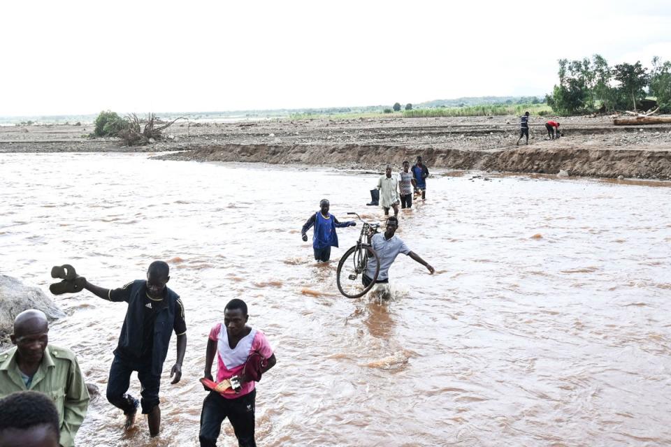 People wade through flood waters caused by last week’s heavy rains caused by Tropical Cyclone Freddy in Phalombe, southern Malawi on Saturday. Authorities are still getting to grips with destruction in Malawi and Mozambique with over 370 people confirmed dead and several hundreds still displaced or missing (AP)