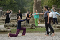 Greek actress Xanthi Georgiou, right, playing the role of the High Priestess, lights the torch during the final rehearsal for the lighting of the Olympic flame at Ancient Olympia site, birthplace of the ancient Olympics in southwestern Greece, Sunday, Oct. 17, 2021. The flame will be transported by torch relay to Beijing, China, which will host the Feb. 4-20, 2022 Winter Olympics. (AP Photo/Thanassis Stavrakis)