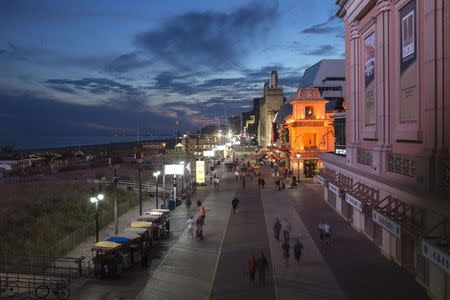 People walk along the boardwalk during sunset in Atlantic City, New Jersey September 15, 2014. REUTERS/Adrees Latif