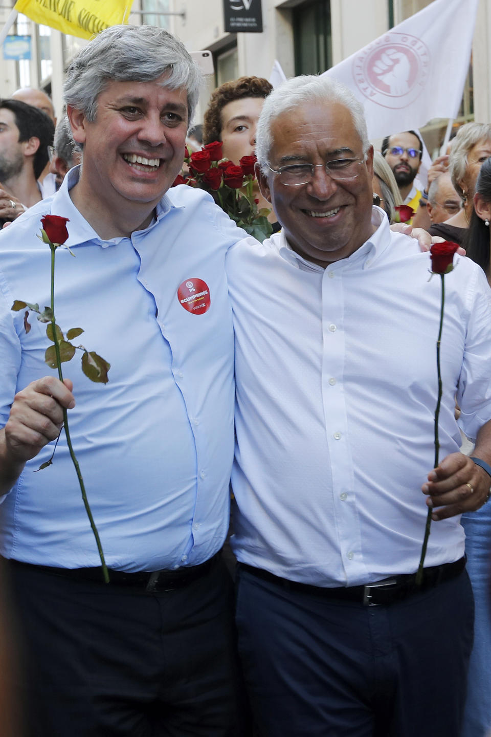 Portuguese Prime Minister and Socialist Party leader Antonio Costa, right, and Finance Minister Masrio Centeno hold roses during an election campaign action in downtown Lisbon Friday, Oct. 4, 2019. Portugal will hold a general election on Oct. 6 in which voters will choose members of the next Portuguese parliament. The ruling Socialist Party hopes an economic recovery during its four years of governing will persuade voters to return the party to power. (AP Photo/Armando Franca)